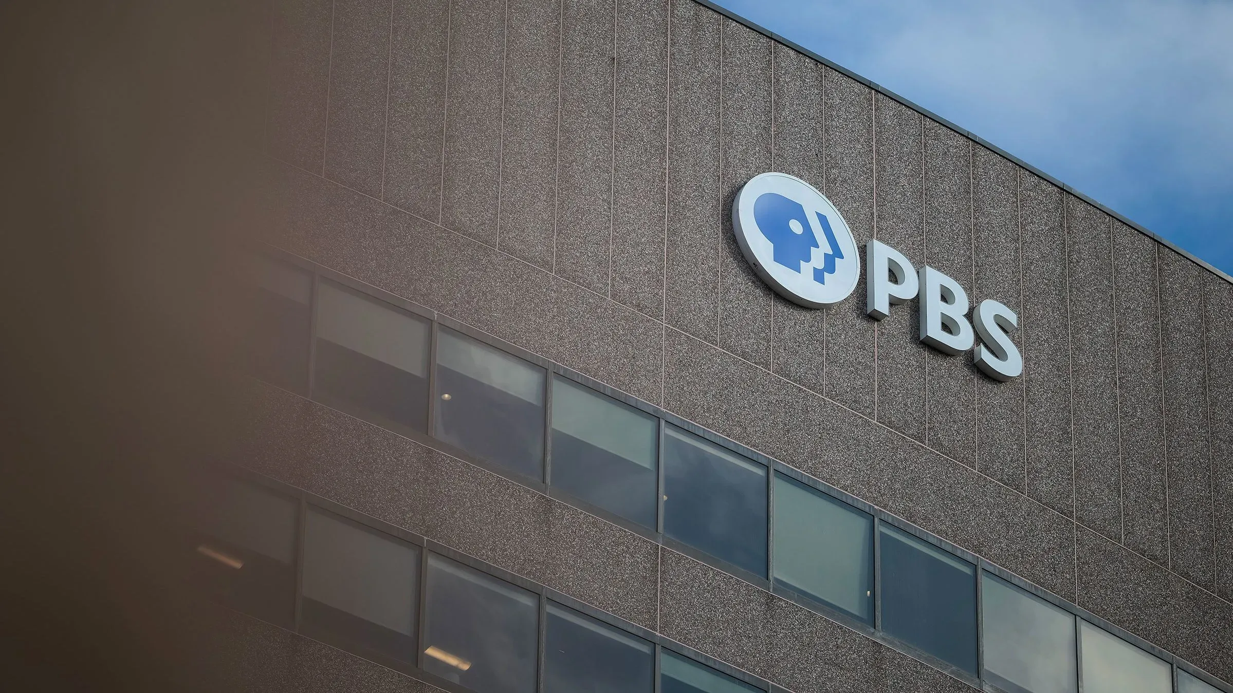 شعار شبكة PBS على واجهة المبنى، يعكس التحديات التي تواجهها الشبكة بعد اقتراح إلغاء التمويل الفيدرالي.