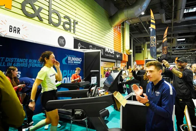 صوفي باور تحتفل بتحطيم الرقم القياسي لأكبر مسافة تقطعها امرأة على جهاز المشي في 48 ساعة، وسط جمهور متحمس في معرض الجري الوطني.