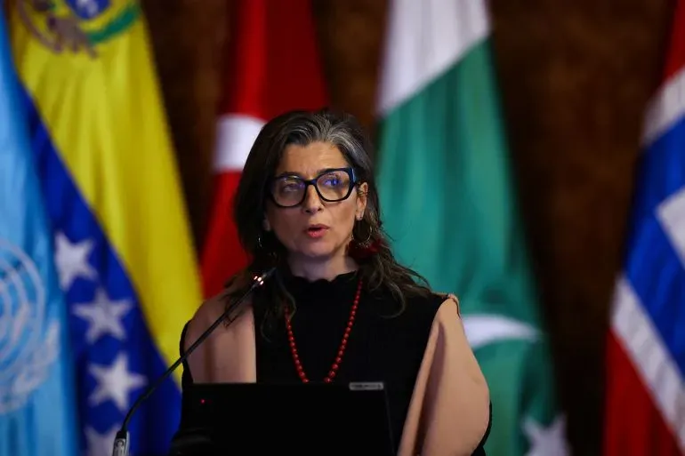 فرانشيسكا ألبانيز، المقررة الخاصة للأراضي الفلسطينية، تتحدث في مؤتمر دولي في بوغوتا حول الإبادة الجماعية في غزة، وسط أعلام دول مختلفة.