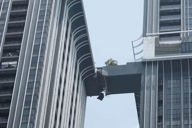 جسر يربط بين مبنيين سكنيين في بانكوك، يظهر تضرره بعد الزلزال، مع شجرة تنمو على حافة الهيكل المتضرر.