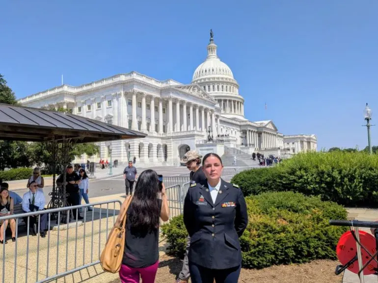 امرأة ترتدي زيًا عسكريًا تقف أمام مبنى الكابيتول الأمريكي، حيث تجمع المحاربون القدامى والمتظاهرون للاحتجاج على أزمة الجوع في غزة.