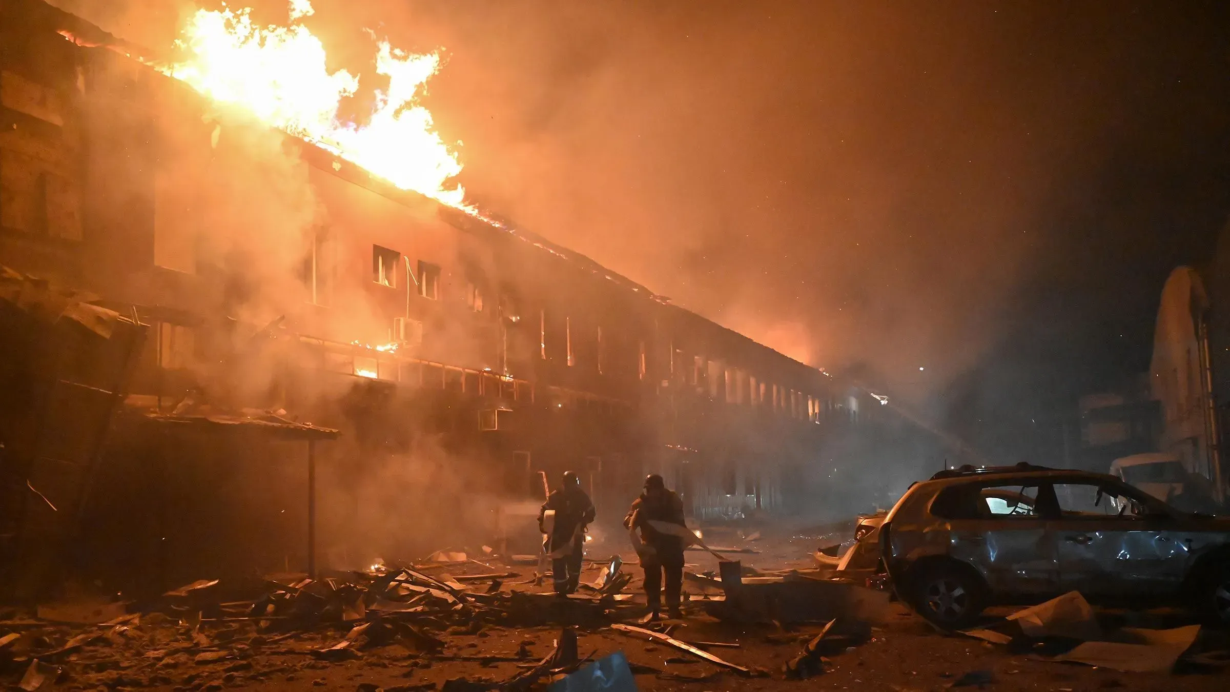 مشهد لحريق كبير في مبنى مدمر، حيث يظهر رجال الإطفاء يعملون وسط الدخان والأنقاض، مما يعكس آثار الحرب المستمرة في أوكرانيا.