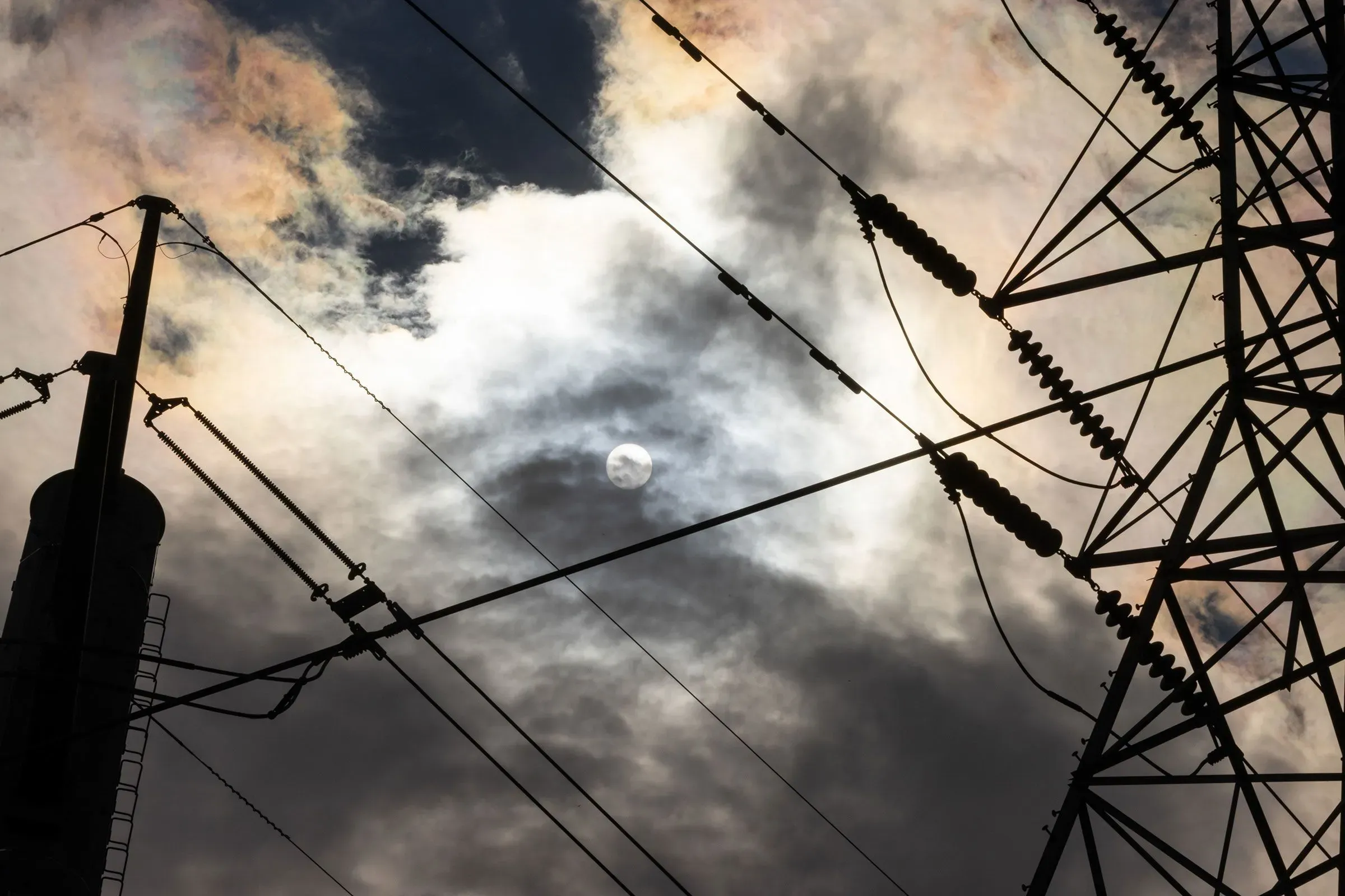 ارتفاع أسعار الطاقة ينعكس في صورة لأسلاك كهربائية وأبراج نقل تحت سماء ملبدة بالغيوم، مما يعكس أزمة فواتير الخدمات العامة.