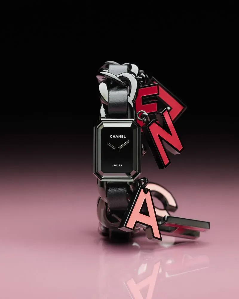 ساعة شانيل بتصميم عصري، مزودة بسوار جلدي أسود وعناصر زخرفية ملونة، تعكس الأناقة والابتكار في صناعة الساعات الفاخرة.