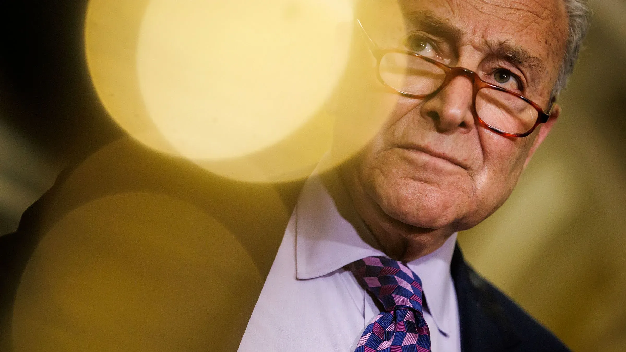 تشاك شومر، زعيم الأقلية في مجلس الشيوخ، يبدو جادًا أثناء مناقشات حول استراتيجيات التمويل الحكومي، مع خلفية ضبابية تعكس التحديات السياسية المقبلة.