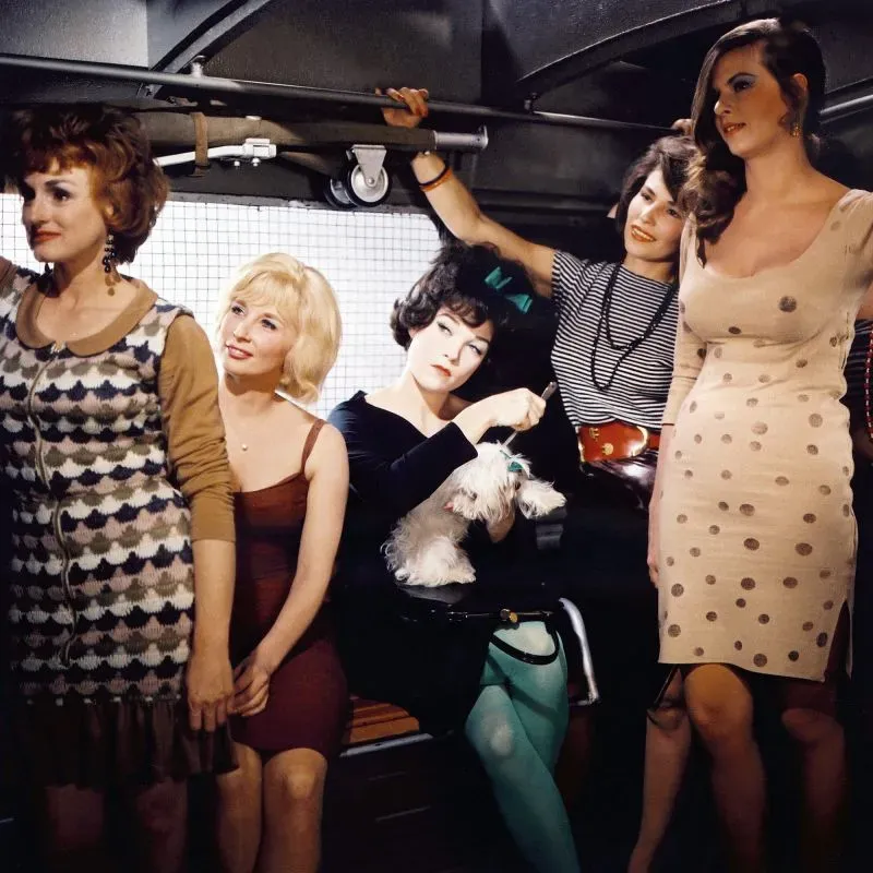 مجموعة من النساء يرتدين أزياء متنوعة في بيئة حضرية، تعكس أسلوب الخياطة الراقية وتأثيرات الموضة، مما يتماشى مع موضوع فيلم ويس أندرسون الجديد.