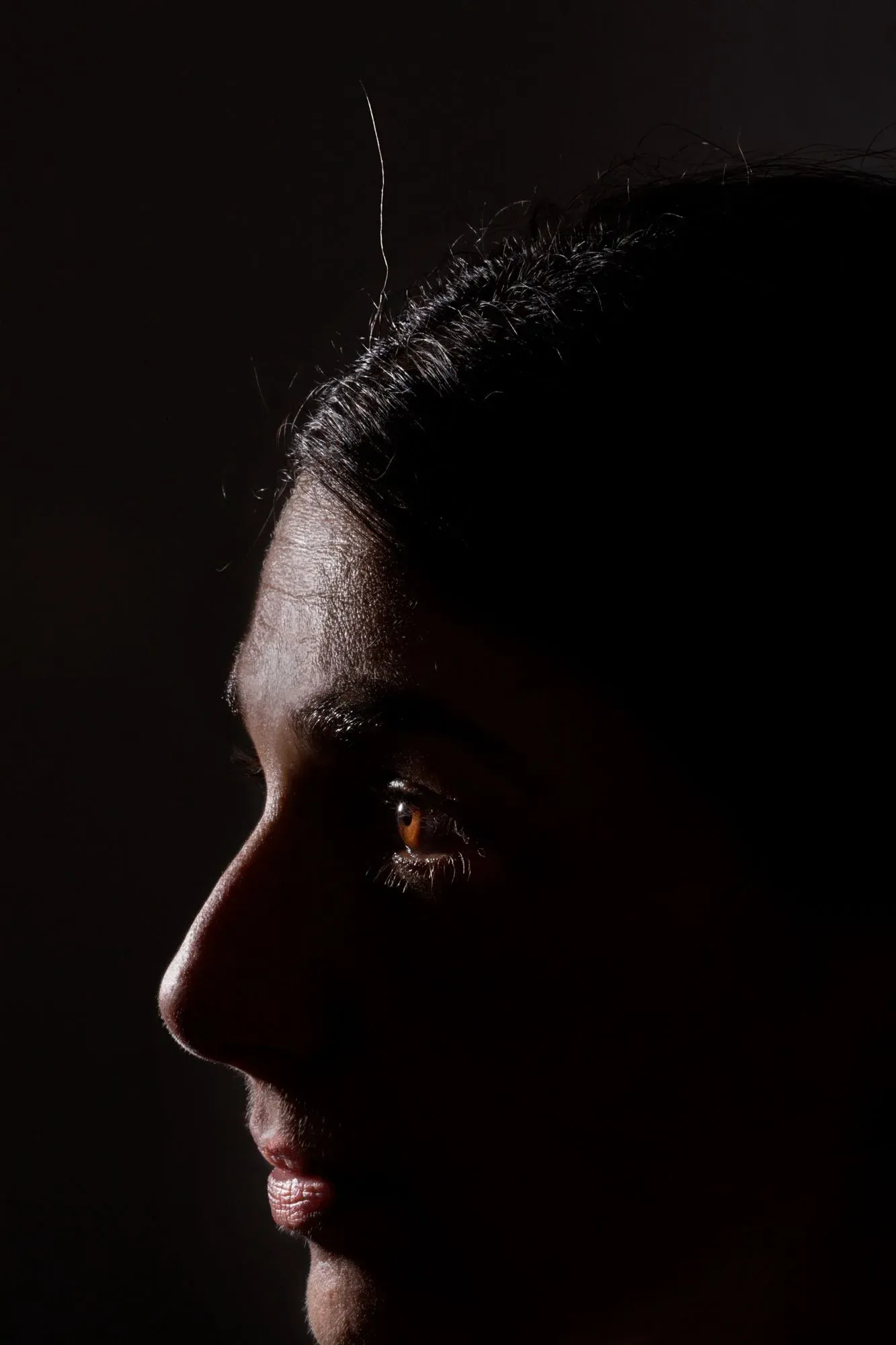 صورة جانبية لامرأة ذات شعر داكن تظهر تفاصيل وجهها، مع تسليط الضوء على عينيها، تعكس مشاعر القلق حول الشيخوخة.