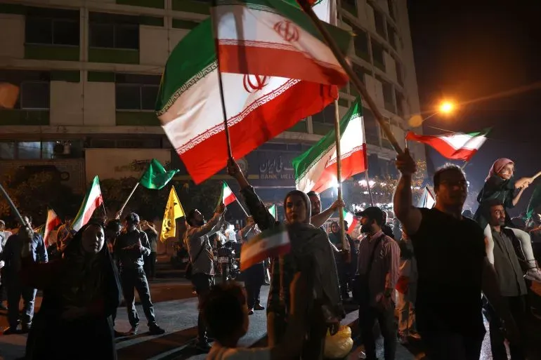 محتجون يحملون الأعلام الإيرانية في مظاهرة ليلية، تعبيرًا عن دعمهم لإيران عقب الهجمات العسكرية على قاعدة العديد في قطر.