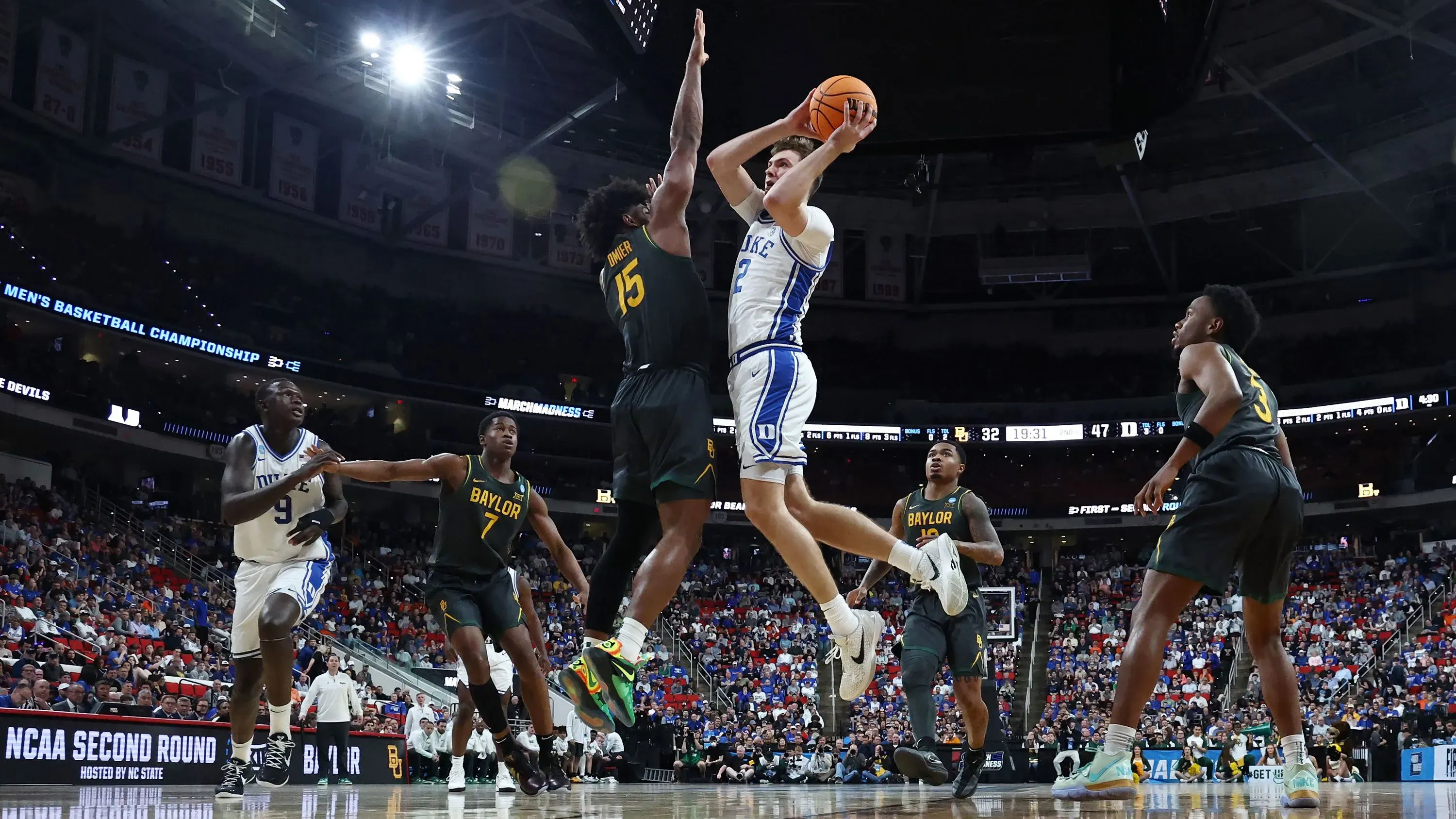 لاعب من فريق ديوك يسجل نقطة خلال مباراة ضد بايلور في بطولة NCAA، مع وجود لاعبين من الفريق الخصم في الخلفية.
