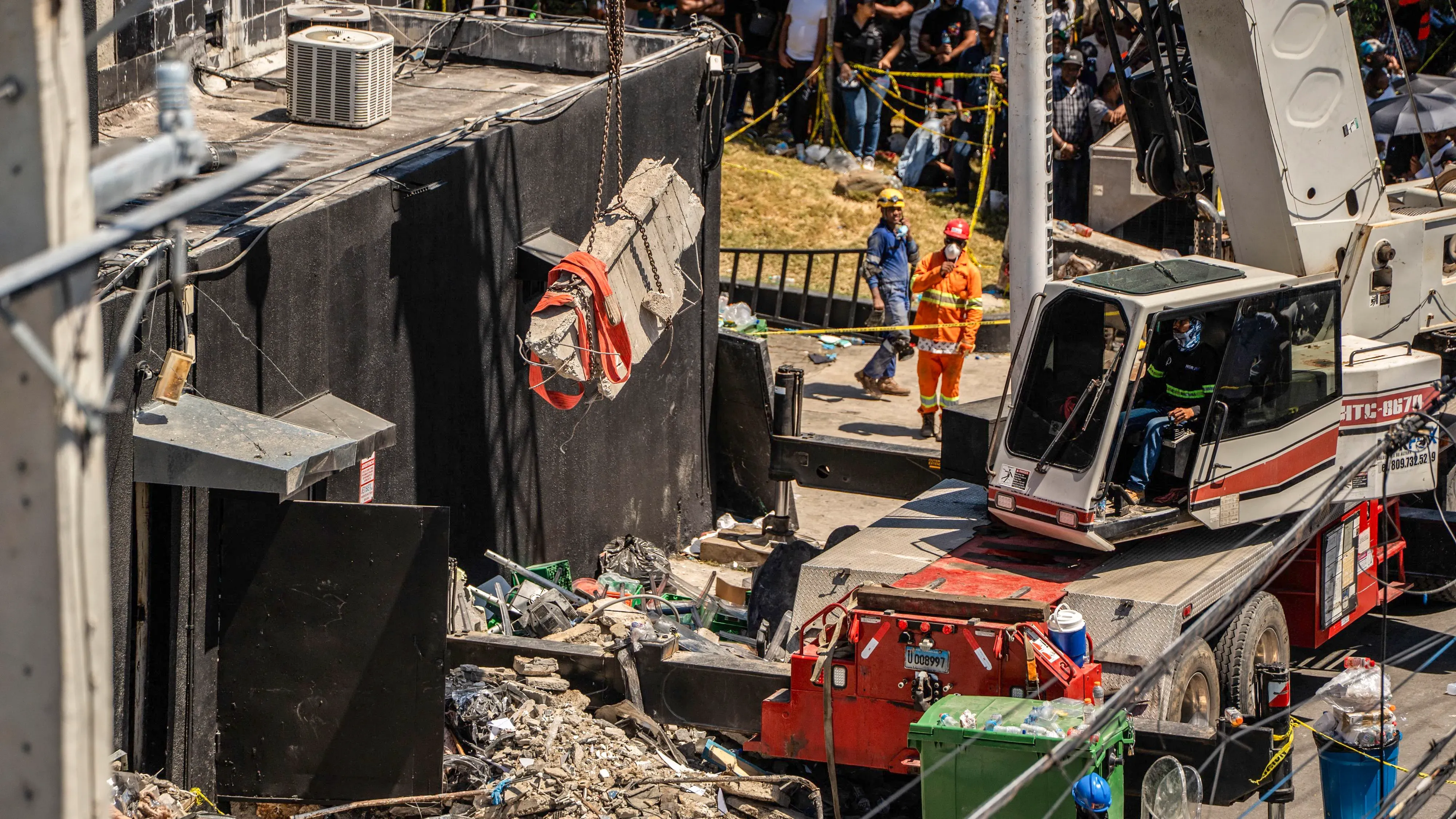 مشهد من موقع انهيار ملهى جيت سيت في سانتو دومينغو، يظهر جهود الإنقاذ مع رافعة وعمال يرتدون زي الطوارئ وسط الحطام.