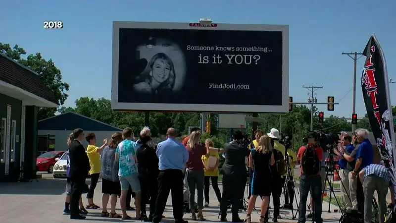 محتجون يقفون أمام لافتة تسأل "هل يعرف أحد شيئًا؟" في حملة للعثور على جودي هويسنترويت، مع صورة لها، في مدينة ماسون سيتي.