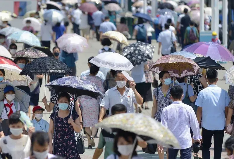 شوارع بيونغ يانغ مزدحمة بالناس الذين يحملون المظلات، معظمهم يرتدون أقنعة وجه، مما يعكس تأثير جائحة كوفيد-19 في كوريا الشمالية.