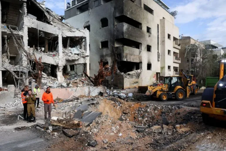 دمار واسع في مبانٍ بطهران بعد الهجمات الجوية، بينما يعمل عمال الإنقاذ على إزالة الأنقاض في موقع الحادث.