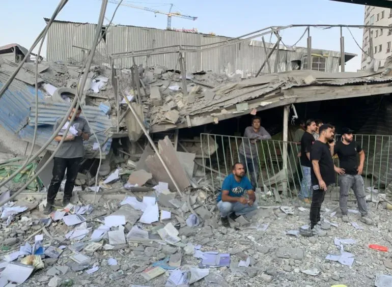 دمار واسع في موقع قصف إسرائيلي، يظهر رجالًا يتفقدون الأنقاض والأضرار في منطقة سكنية بطهران بعد الهجمات.