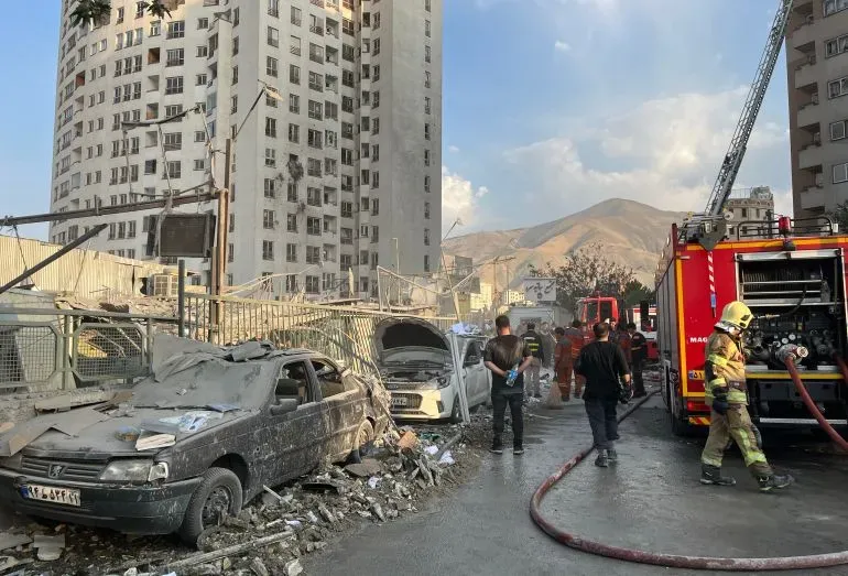 دمار واسع في منطقة سكنية بطهران بعد قصف إسرائيلي، مع وجود رجال إطفاء ومركبات متضررة، مما يعكس تصاعد التوترات العسكرية.