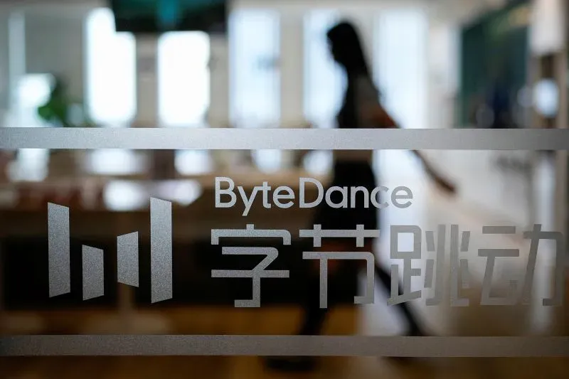 شخصية تسير بجوار شعار شركة ByteDance في مكتبها، مما يعكس المناقشات حول بيع TikTok لإيلون ماسك في ظل الضغوط القانونية.