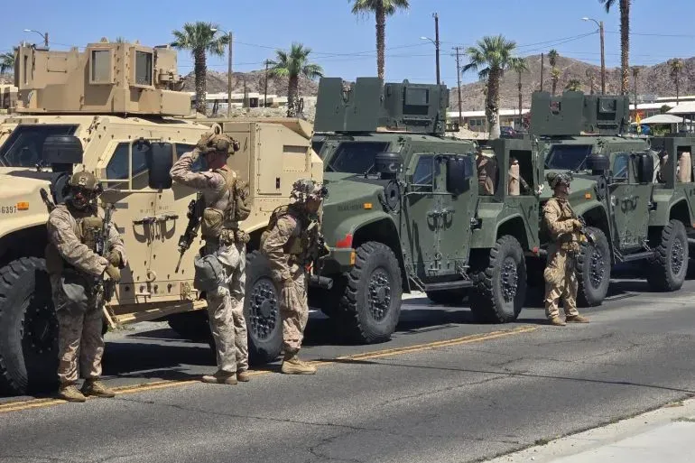 جنود من مشاة البحرية الأمريكية يرتدون زيهم العسكري، يقفون بجانب مركبات مدرعة في لوس أنجلوس، في إطار نشر قوات لمواجهة الاحتجاجات.