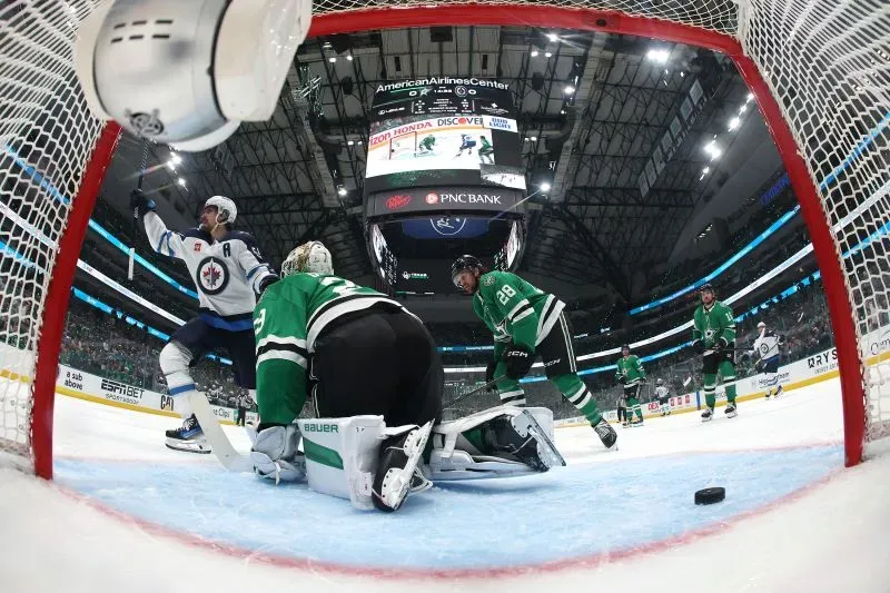 مارك شيفيل يحتفل بتسجيل هدف في مباراة هوكي بين وينيبيج جيتس ودالاس ستارز، مع زملائه في الفريق في خلفية الملعب.