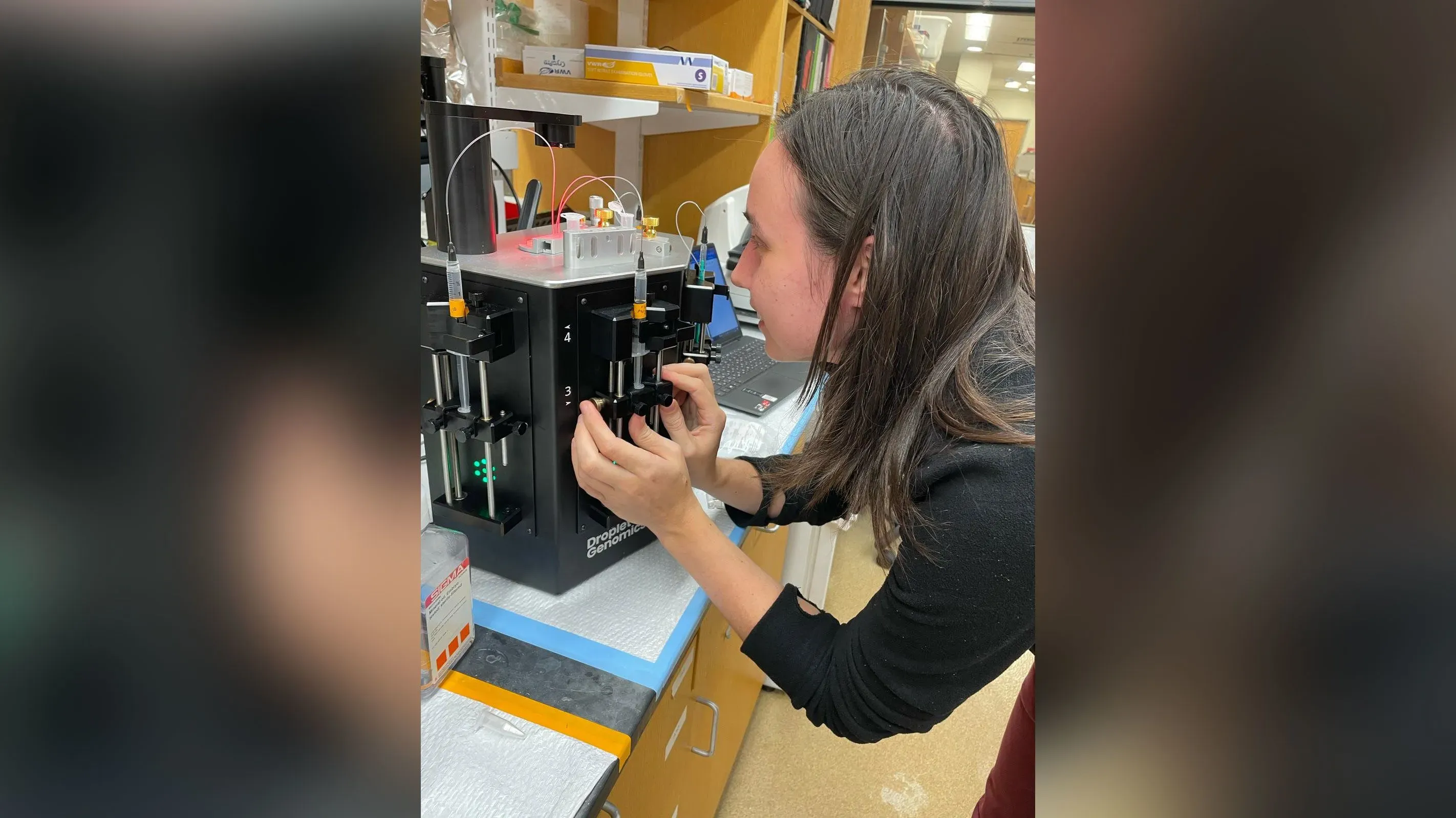 باحثة تعمل في مختبر، تُجري تجارب على جهاز علمي، في سياق قضية تتعلق بإلغاء تأشيرتها بسبب عدم التصريح عن أجنة الضفادع.