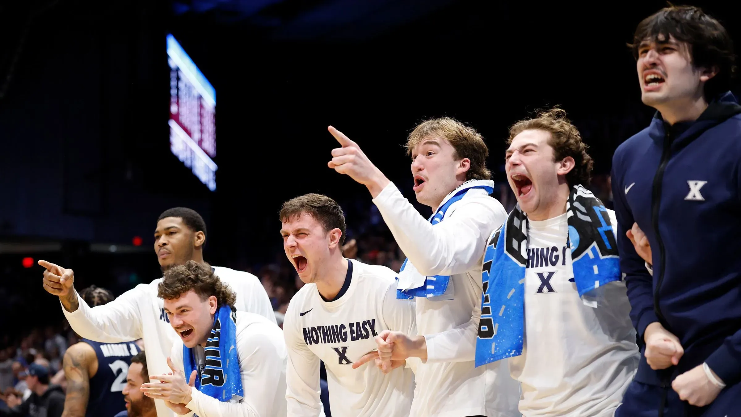 مجموعة من لاعبي فريق كزافييه يحتفلون بحماس بعد الفوز في مباراة كرة السلة، مع تعبيرات فرح واضحة وارتداء قمصان تحمل شعار الفريق.